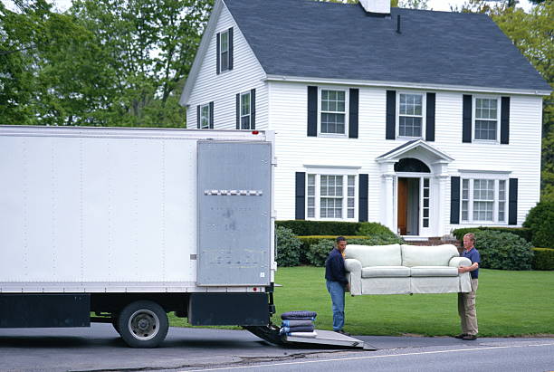 Two Young Male Movers are loading a Sofa in a trailer